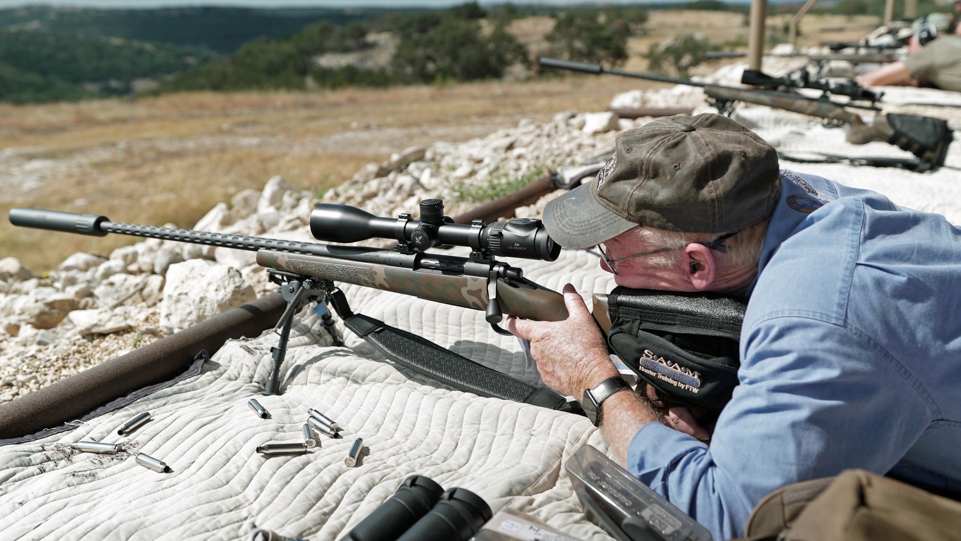 On the range with a left-hand X Custom 7 mm Rem. Mag. For proper cheek weld from the prone position Boddington used a strap on cheekpiece. All test rifles wore suppressors, which made shooting very pleasant.