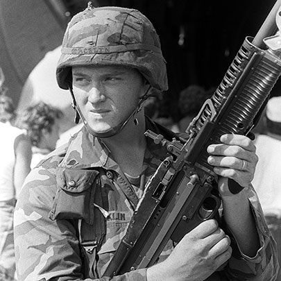 Covering the evacuation of American students, a US soldier cradles a M60 general-purpose machine gun.