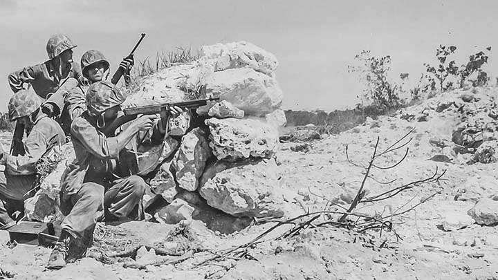 Marines of the 1st Marine Division fighting from the cover of a coral knob. Note that the Marine in front is firing an M1928A1 Thompson submachine gun that is equipped with the simplified L-sight. OFFICIAL USMC PHOTOGRAPH.