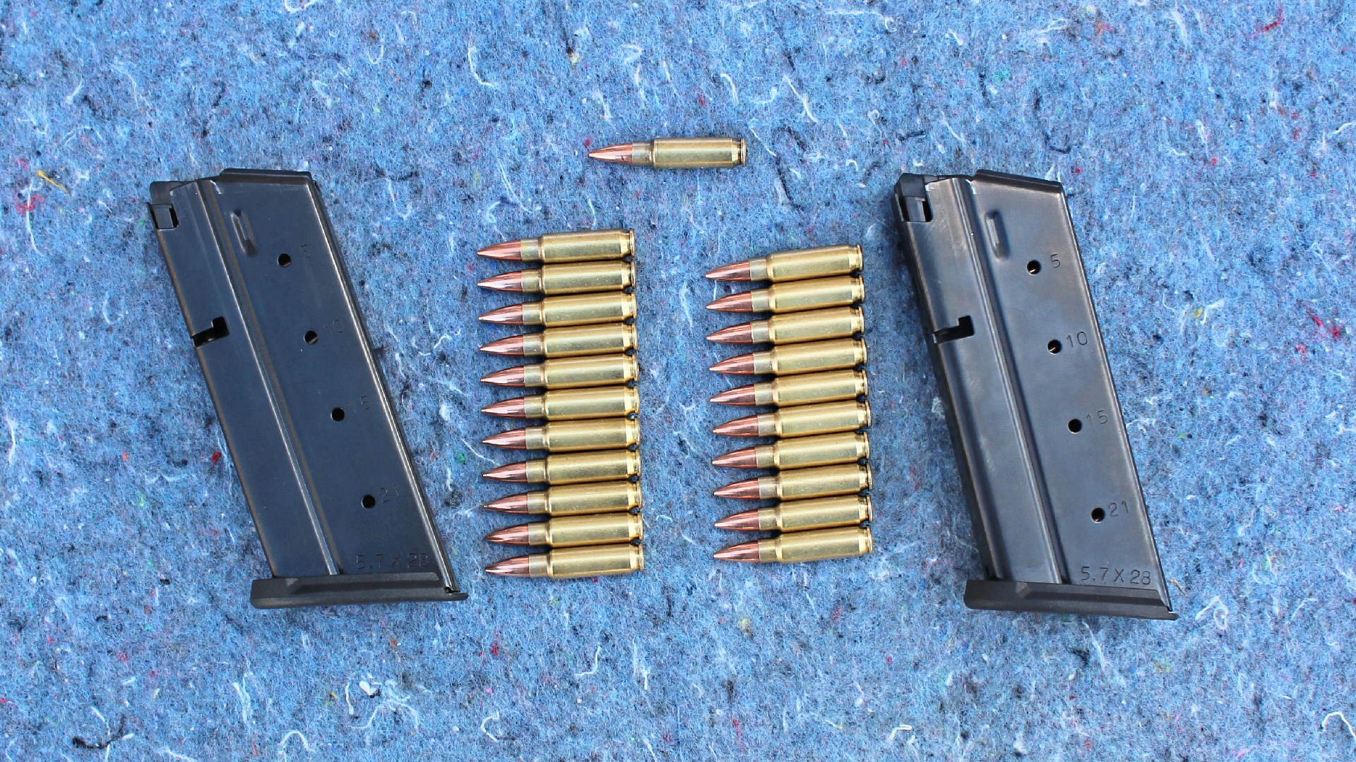 Detachable box magazines for PSA 5.7 Rock 5.7x28 mm FN ammuntion brass cartridges on blue stone background