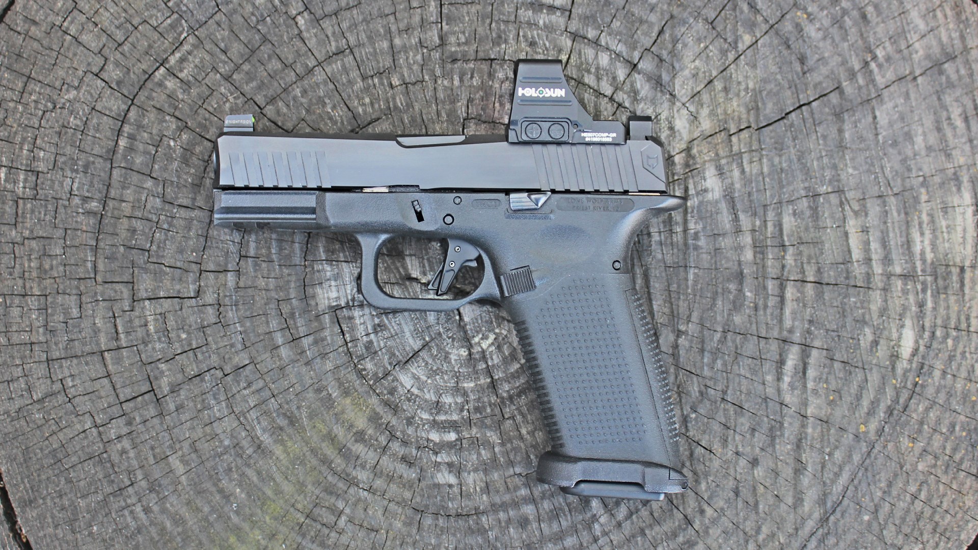 Left-side view Lone Wolf Timberwolf 19x pistol black gun shown with Holosun red-dot optic on wood stump