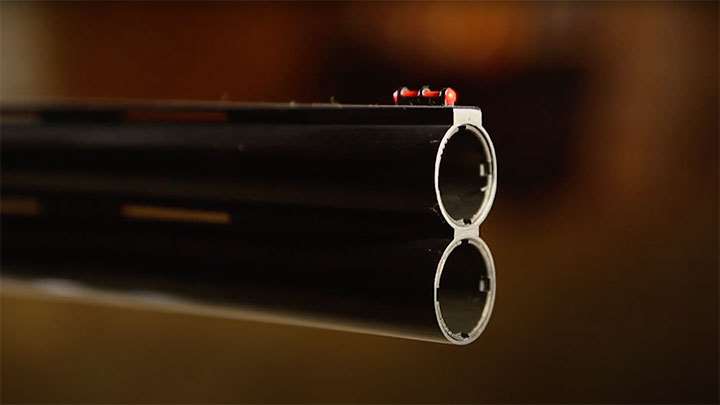 The front of the barrel with red fiber-optic bead and adjustable chokes visible.