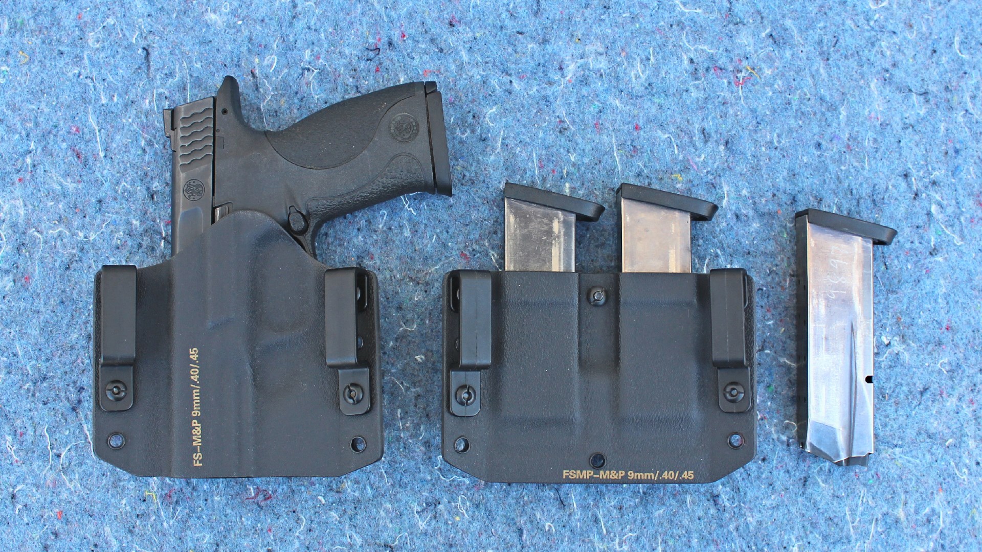 Smith & Wesson M&P 45 shown in holster along with magazines and respective holster on blue background