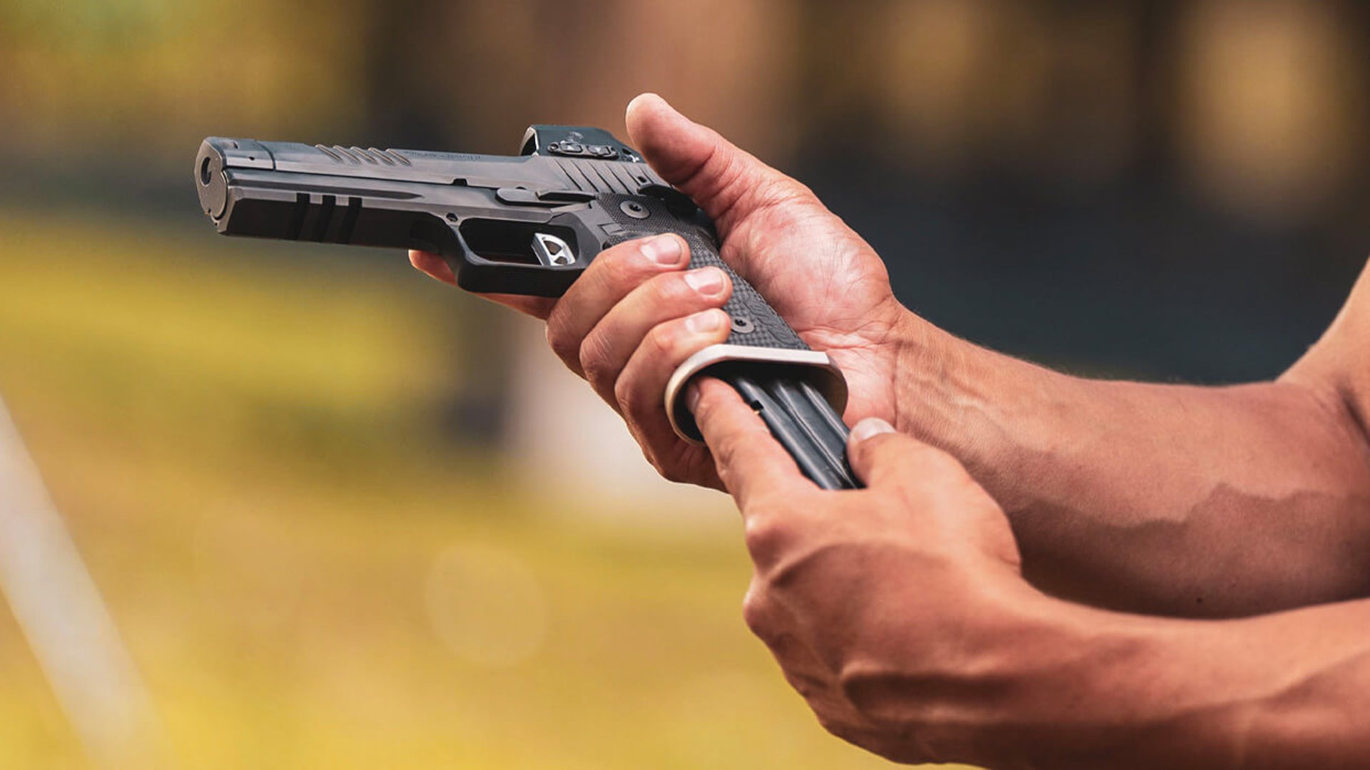 Man inserting a magazine into the bottom of the SIG Sauer P211-GTO.
