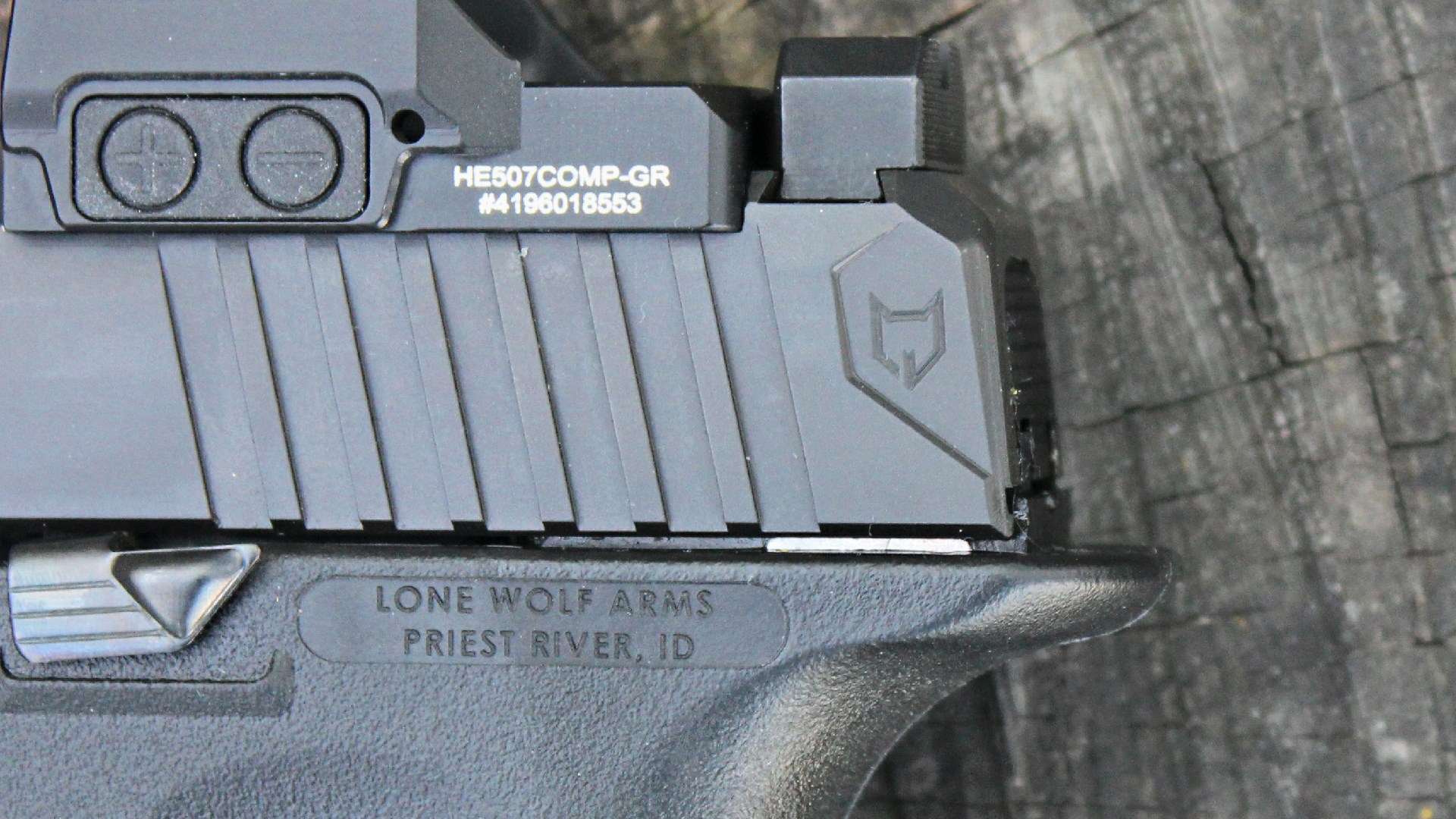 Lone Wolf Arms logo engraved in rear of pistol slide Timberwolf 19X shown with Holosun red-dot optic plate above near black rear sight and below is a black polymer frame shown on wood background