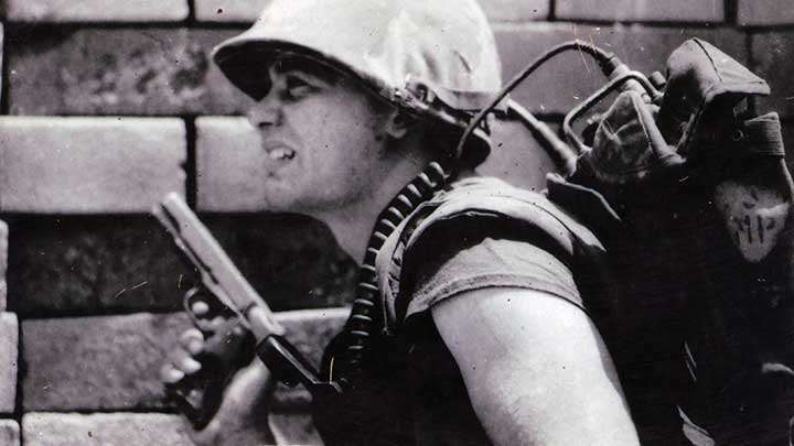 A Marine radioman with his M1911 .45 ACP pistol at the ready during a search and clear mission South of Danang.
