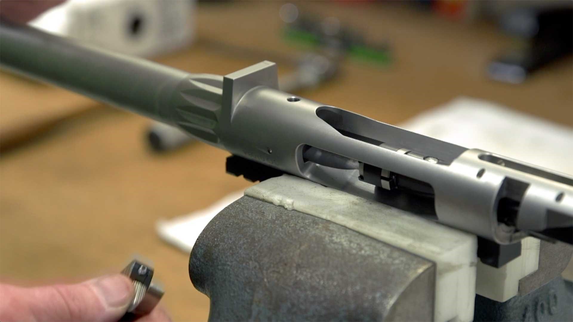 A Rock River Arms bolt-action rifle being assembled on a workbench.