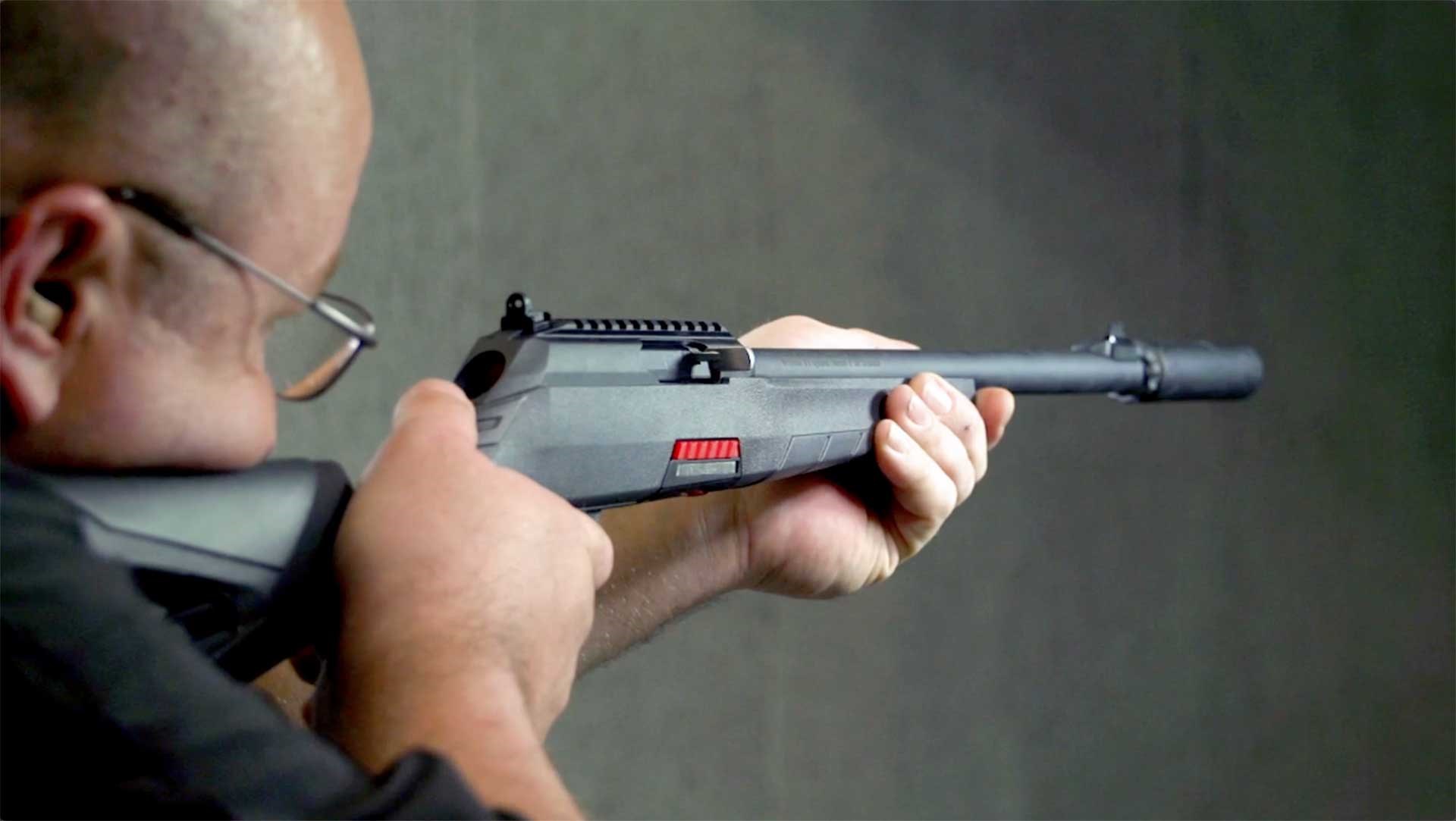A man aiming the gray-colored Winchester Wildcat 22 SR on an indoor range.