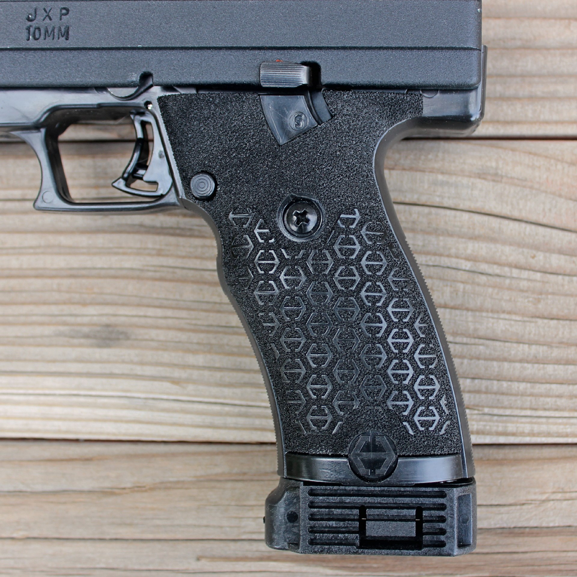 cropped image of JXP 10 pistol semi-automatic gun closeup view grip texturing stipling polymer black shown on wood boards