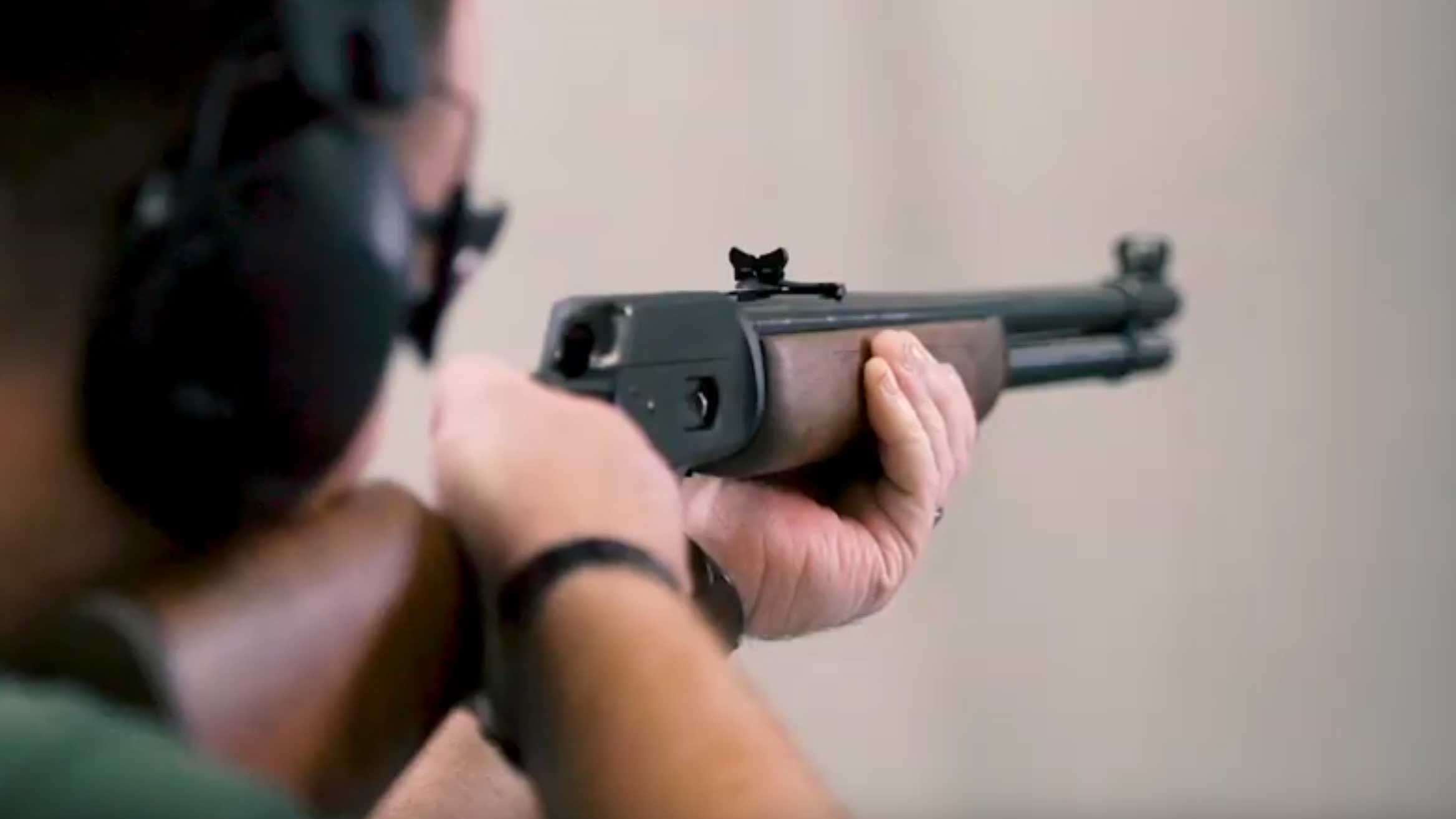 Man on shooting range holding Marlin Model 1894 lever-action rifle.