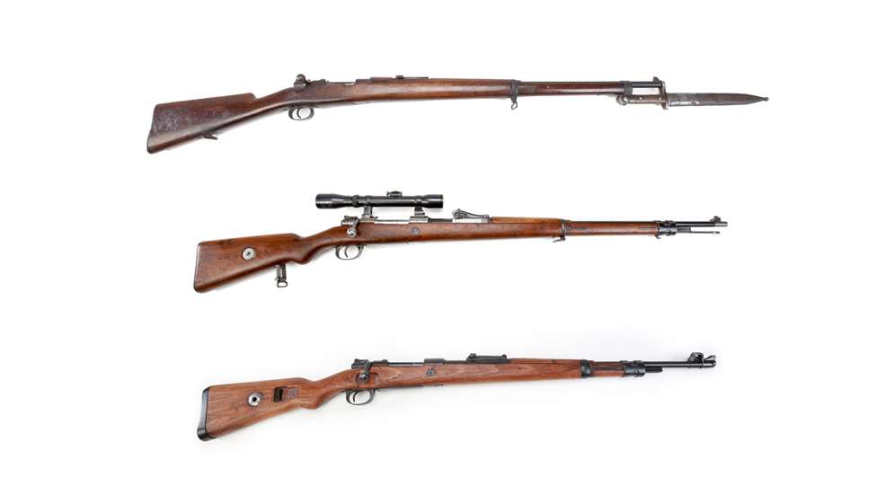 Three mauser rifles bolt-action military german guns in a stack shown with wood stocks sniper version bayonet and carbine