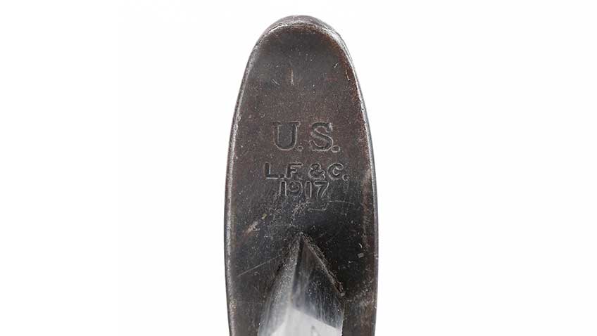 Stamping on pommel of knife with description &quot;U.S. L.F. &amp; C. 1917&quot; shown on white background.