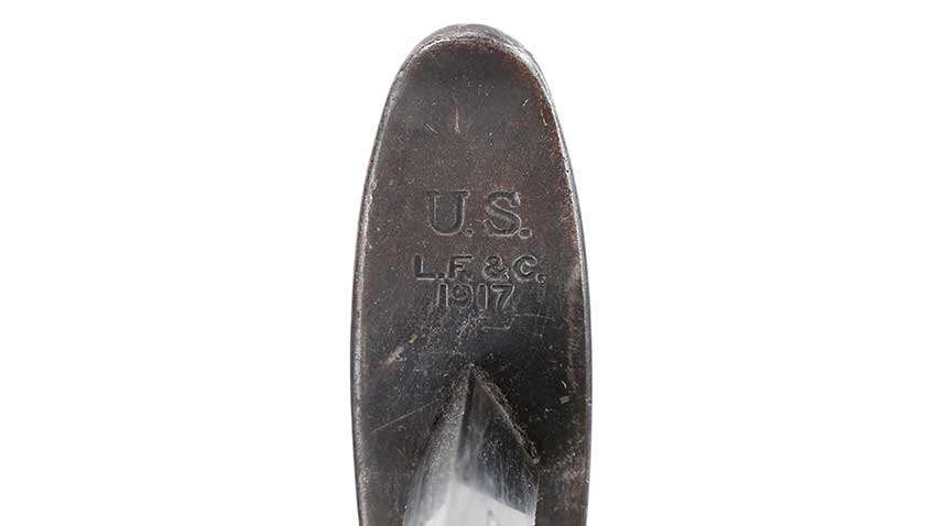 Stamping on pommel of knife with description &quot;U.S. L.F. &amp; C. 1917&quot; shown on white background.