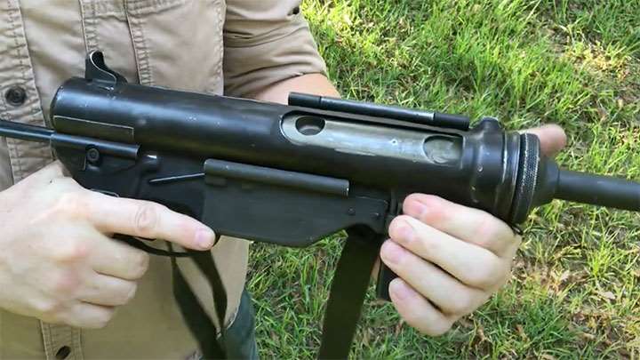 The M3A1 with dust cover flipped open and bolt forward, revealing the charging hole milled into the front of the bolt carrier. This replaced the hand crank on the M3 that was prone to getting damaged with use in the field.