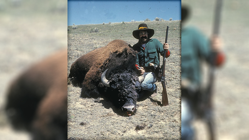 hunter with animal outdoors gun rifle cowboy buffalo sandy blue sky