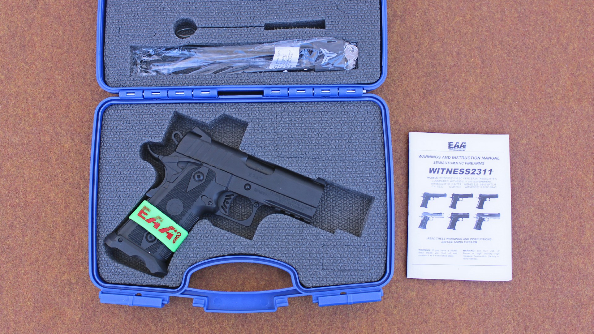 EAA Brat right-side view shown in blue handgun box with accessories and owner's manual at right side on table top-down view