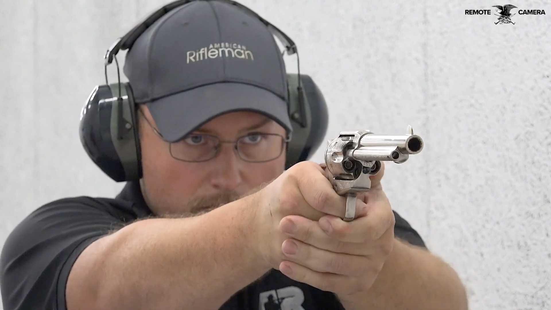 man shooting gun silver revolver baseball cap earmuffs