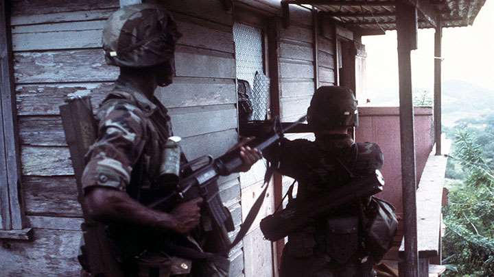The paratroopers come a-knocking. Men of the 82nd Airborne clear houses on their sweep through Grenada. Both carry M16A1 rifles and M72 LAW (66 mm) anti-tank weapons.