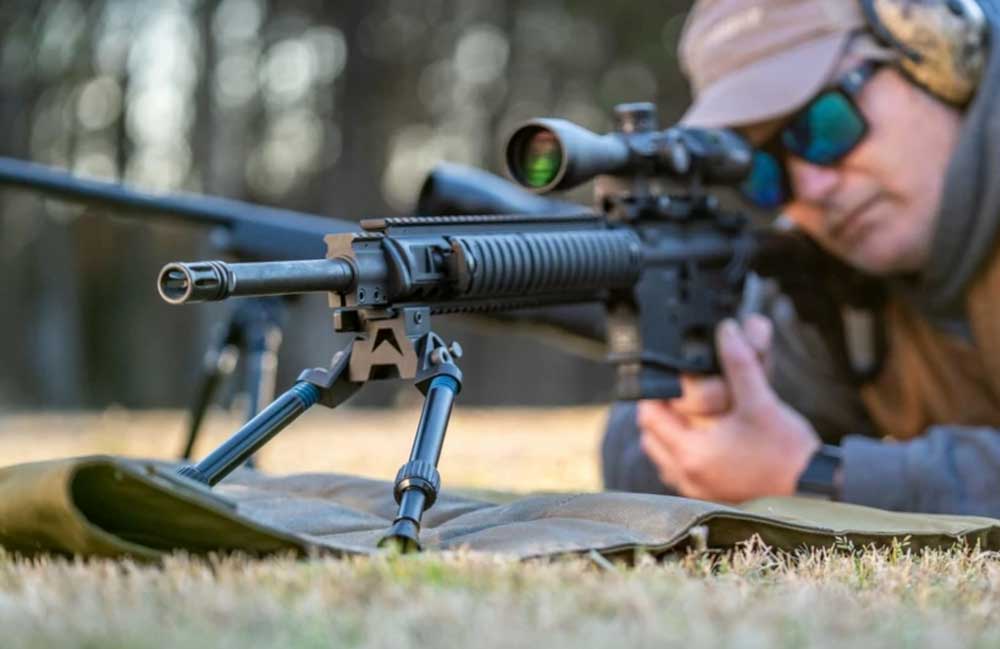 outdoors grass carpet gun rifle man shooting targets bipod legs angle