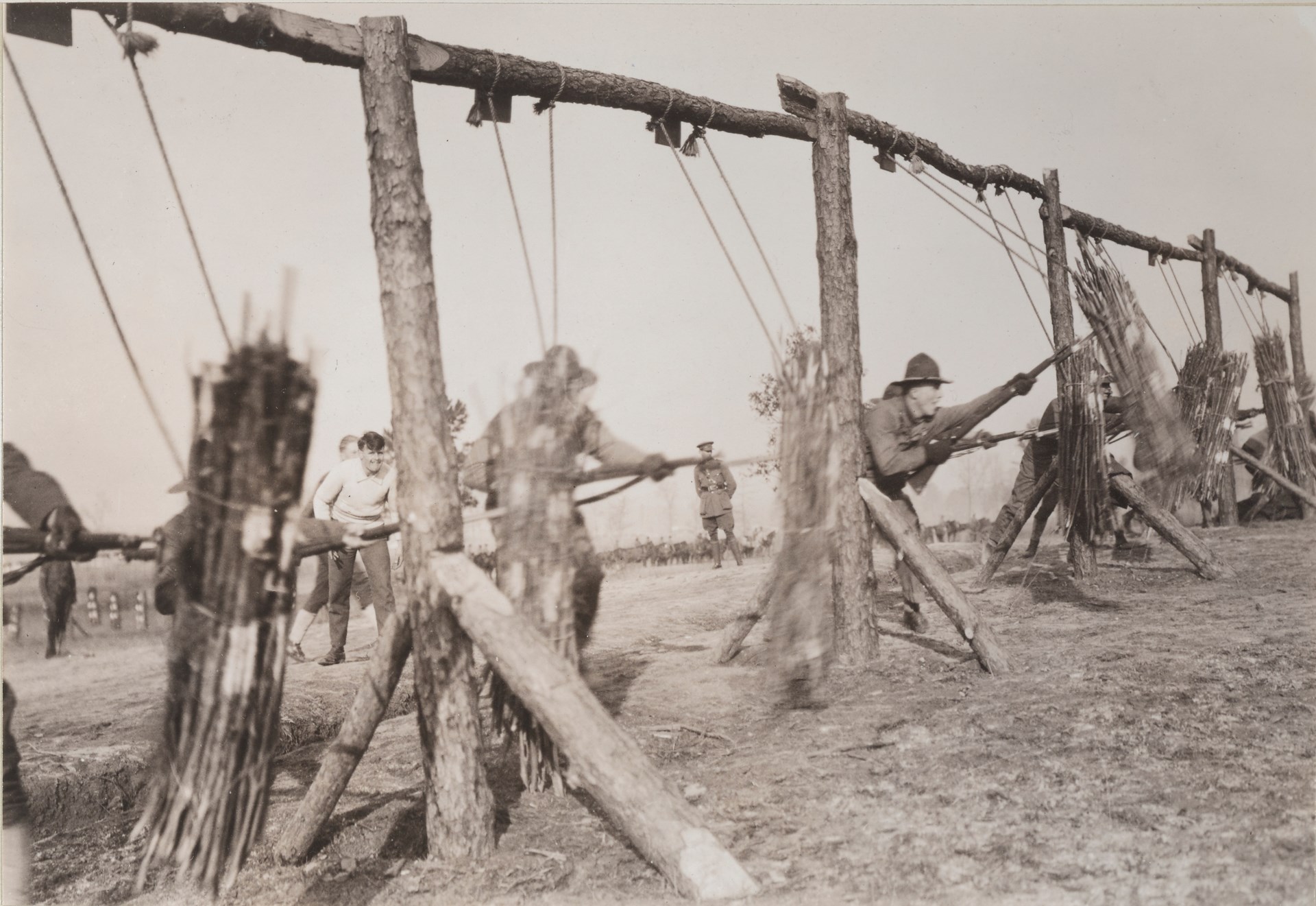 Bayonet training taking place on bundled wooden dummies, teaching the importance of both the thrust and withdrawal on a dynamic target.