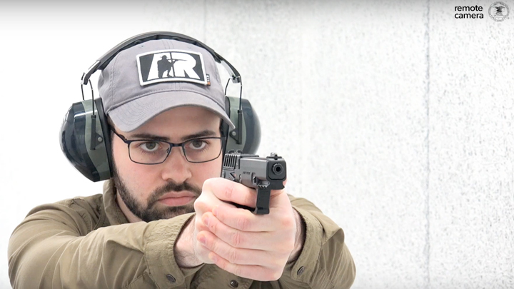 Bearded man with protective shooting gear and gray ballcap shooting a Kel-Tec P17 semi-automatic pistol.