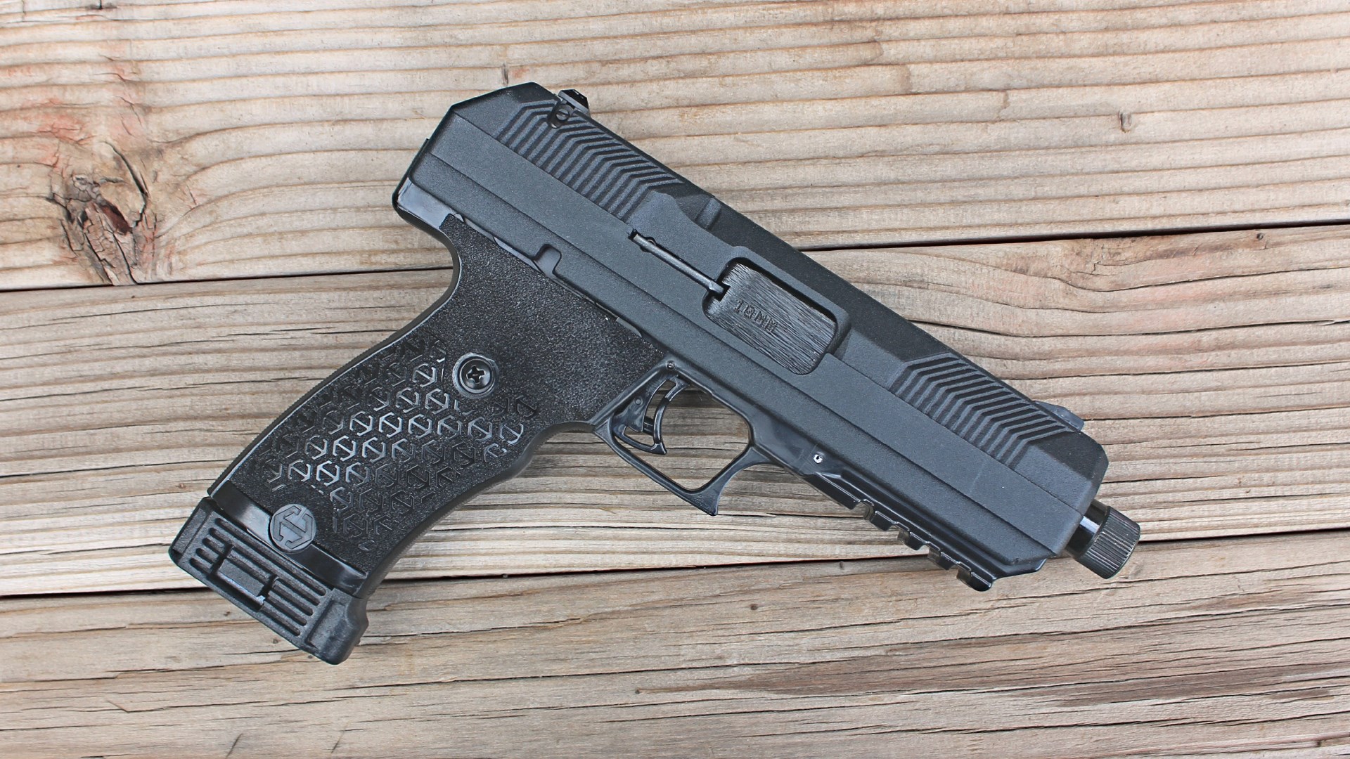 Right-side view of hi-point firearms jxp 10 pistol 10mm auto black gun angled on wood boards