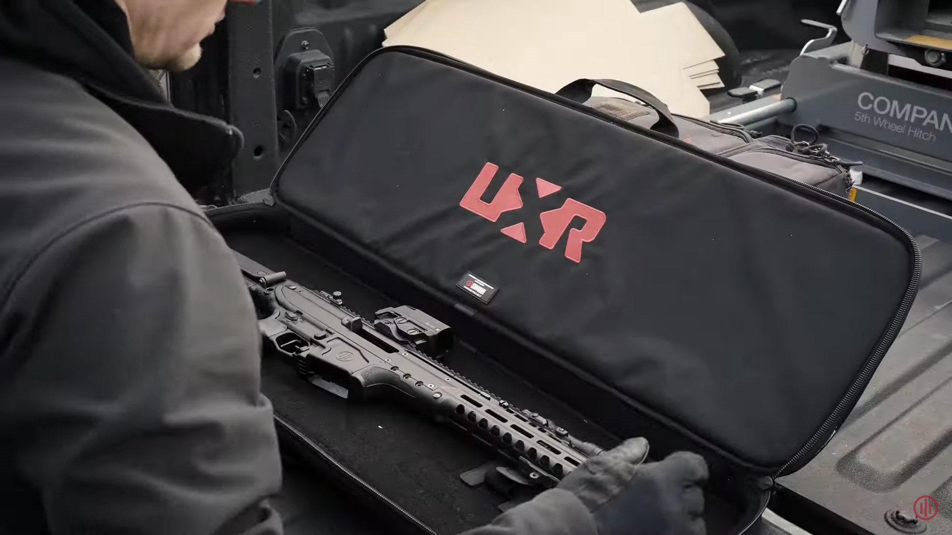 PWS UXR black case red lettering rifle truck bed man over-shoulder