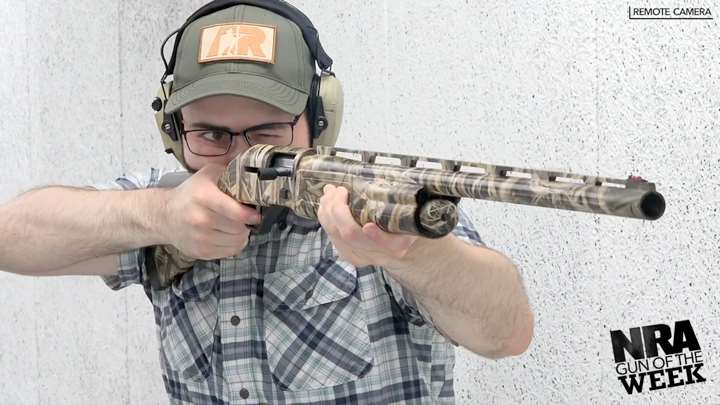 Man wearing a ballcap and protective shooting gear aiming a waterfowl shotgun.