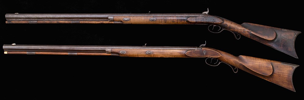 left-side view of two Hawken rifles wood stock black background