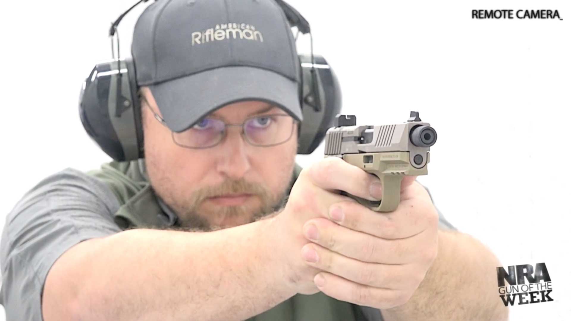 Man wearing protective gear shooting FN 502 semi-automatic hammer-fired rimfire pistol white shooting range