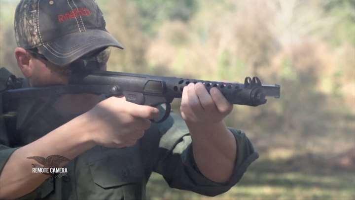 Quartering-view of a man shooting a L2A3 Sterling SMG.