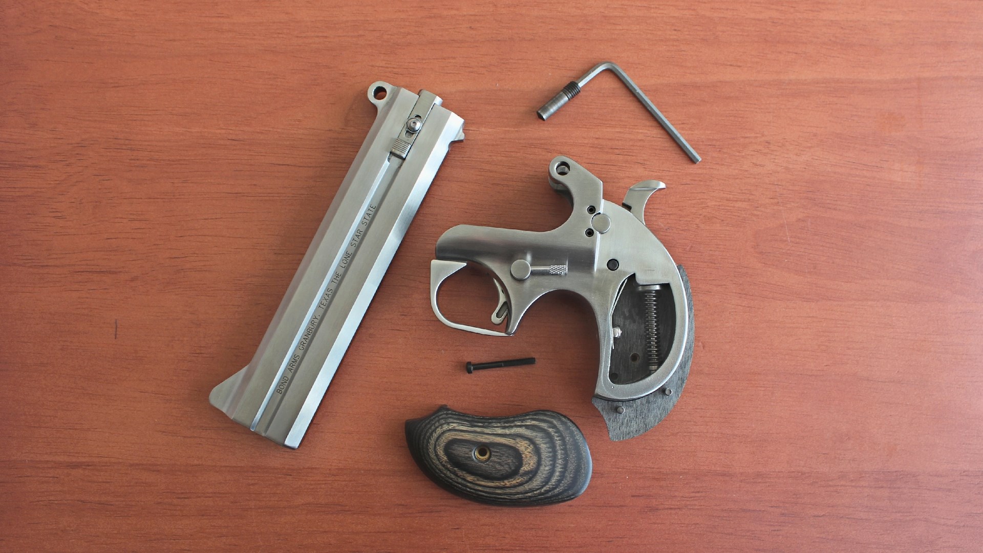 An array of Bond Arms derringer components on a wood table top.