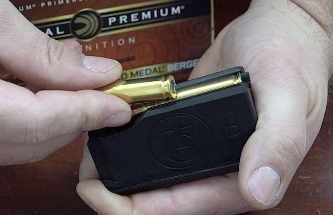 Rifle magazine in hand showing loading brass with Federal Premium ammunition box in background.