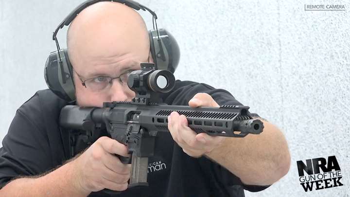 Man wearing protective shooting gear on a shooting range holding a black rifle in his hands.