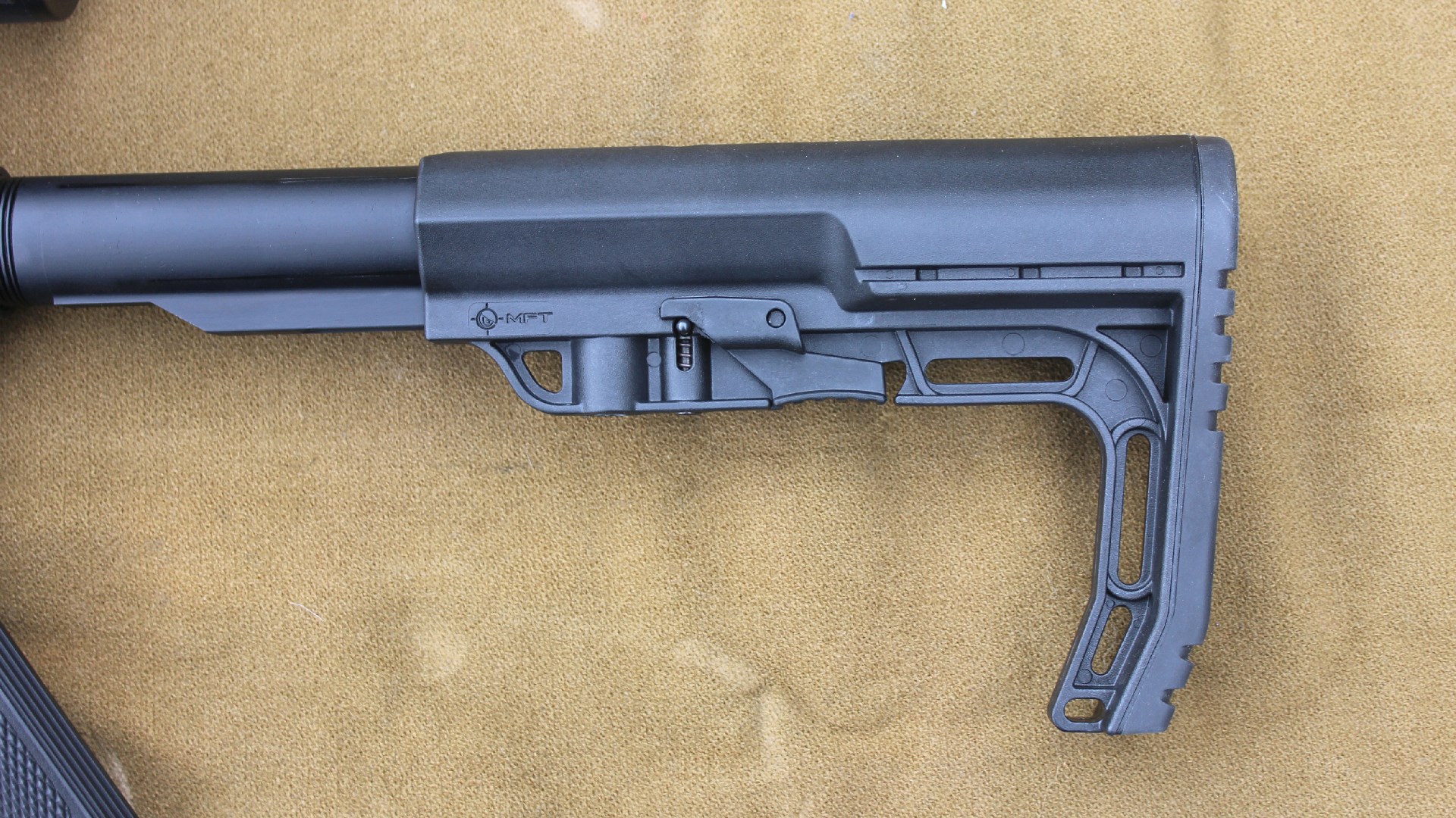 Mission First Tactical MFT Minimalist adjustable stock left-side view black plastic shown on brown cloth background