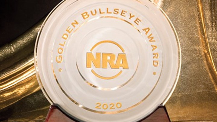 Round frosted-glass award stamped with &quot;2020 NRA Golden Bullseye Award&quot; with golden drapes in the background.