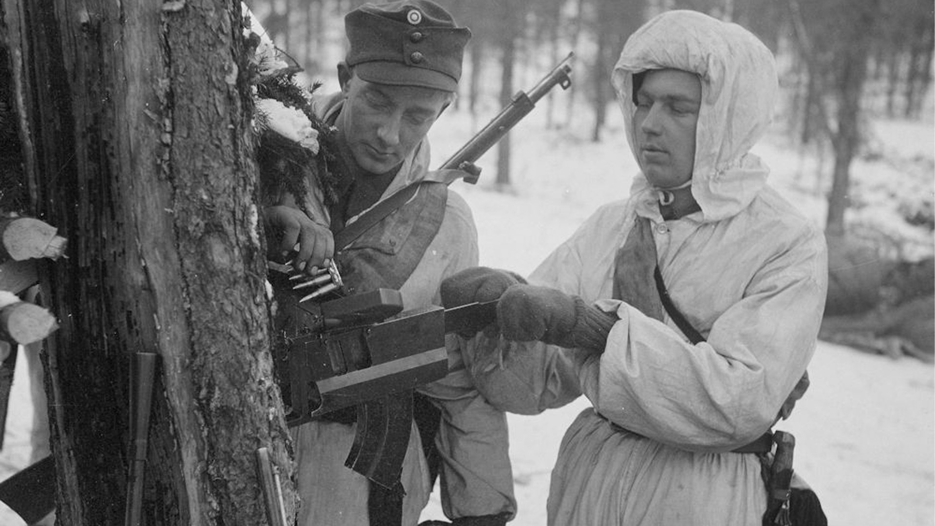 Finnish soldiers in snow-covered forest bucked agains tree loading magazines for M/26 light machine gun