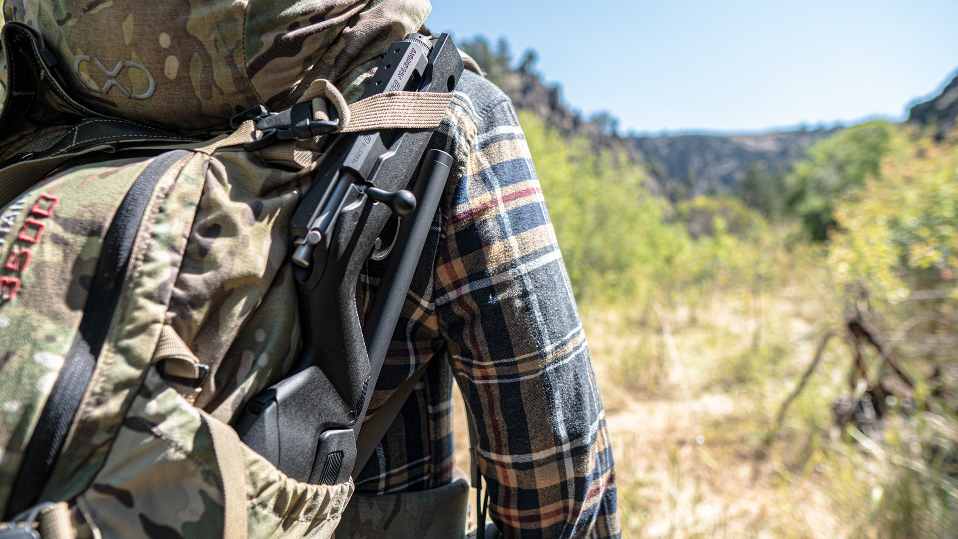 Man carrying the Tactical Solutions Owyhee Magnum rifle on the side of an outdoor pack.