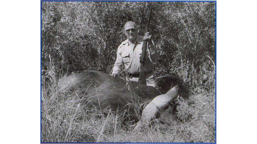 Col. Jeff Cooper posing with "Baby," his .460-caliber big-bore hunting rifle behind a water buffalo.