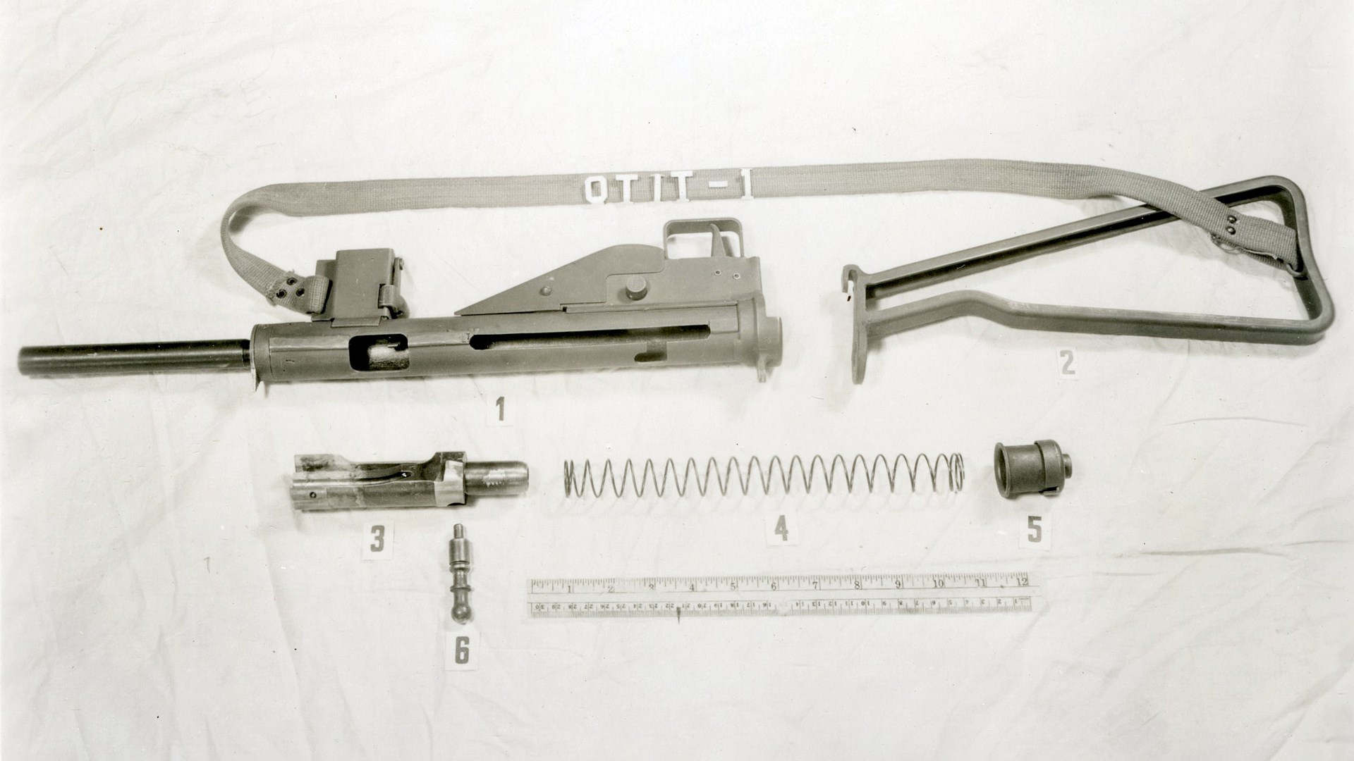 MP 3008 submachine gun upside down with sling exploded parts view disassembled on cloth shown with metal ruler for scale