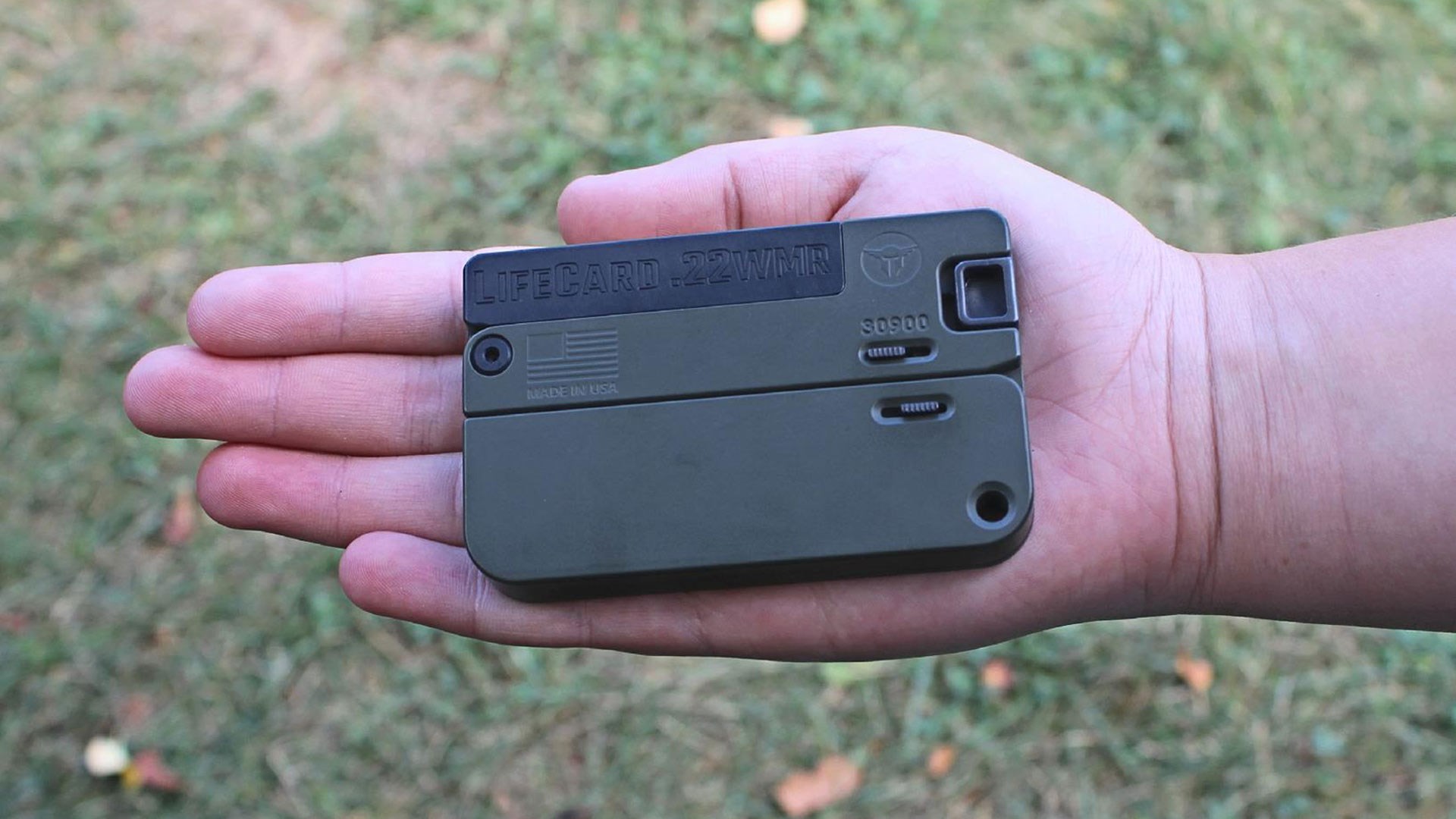 LIfecard folding pistol 22 MAG WMR gun in hand outdoors grass background