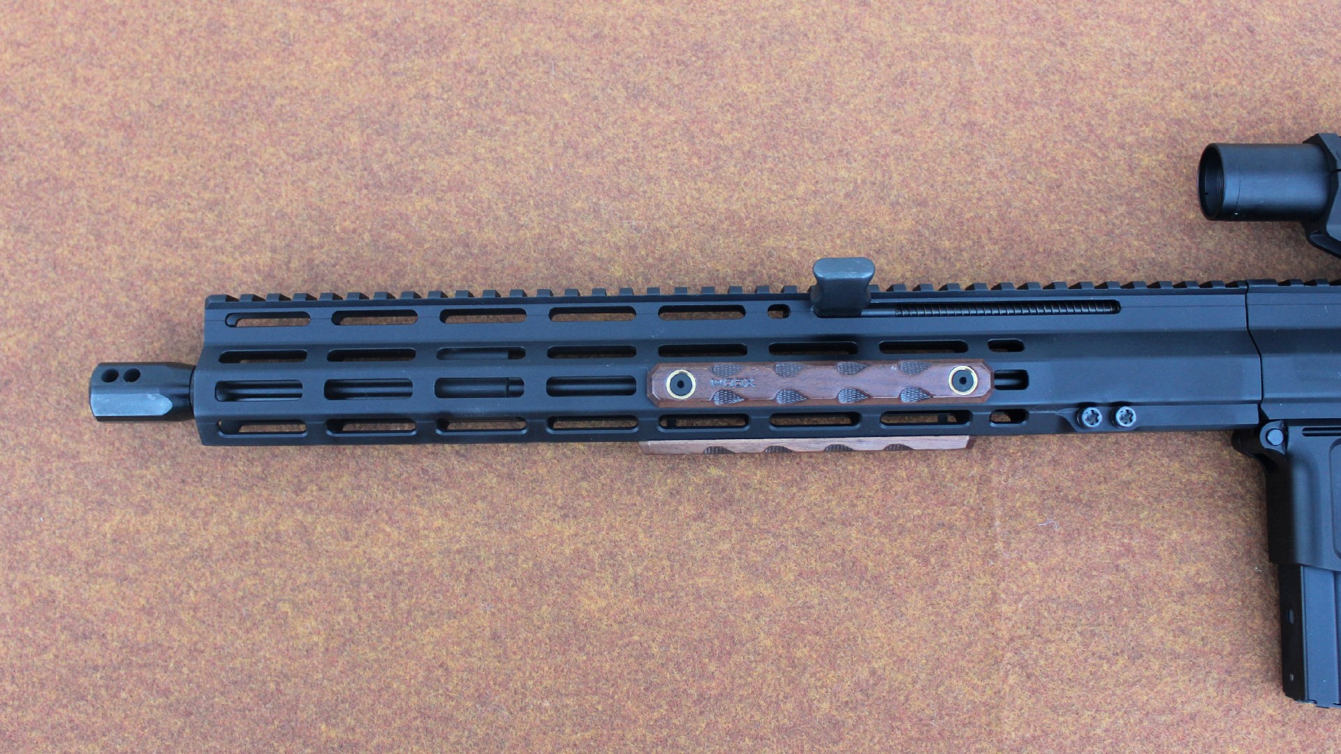 FM Products Rancher left-side closeup of handguard with g10 scales inserted in M-Lok slots along aluminum barrel poking out on left with muzzle brake