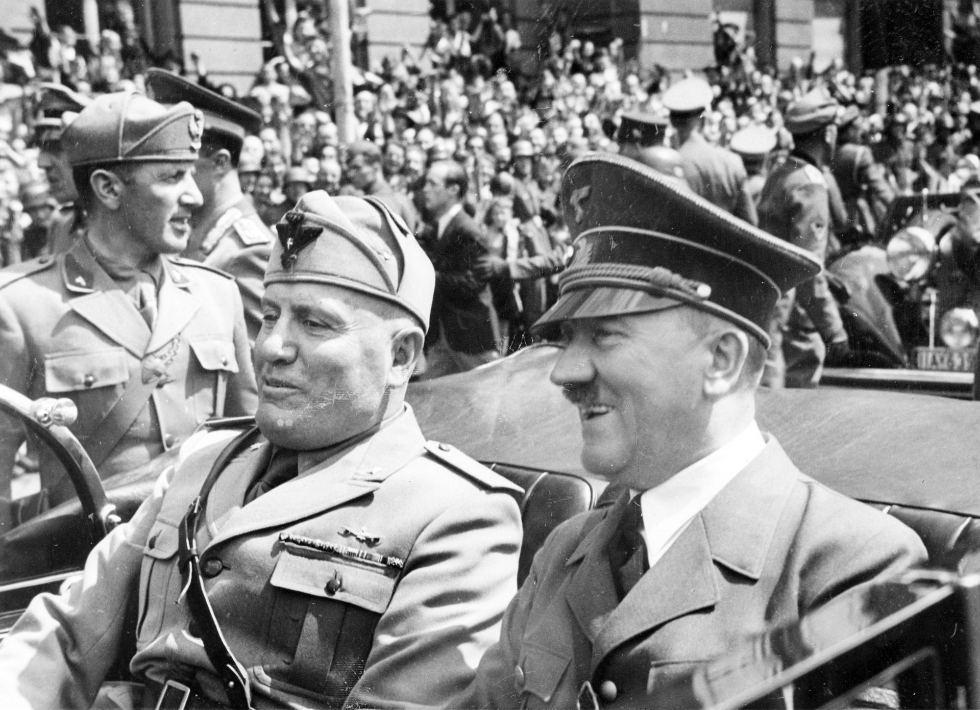 Hitler and Mussolini riding together in open-top car during a military parade black/white image