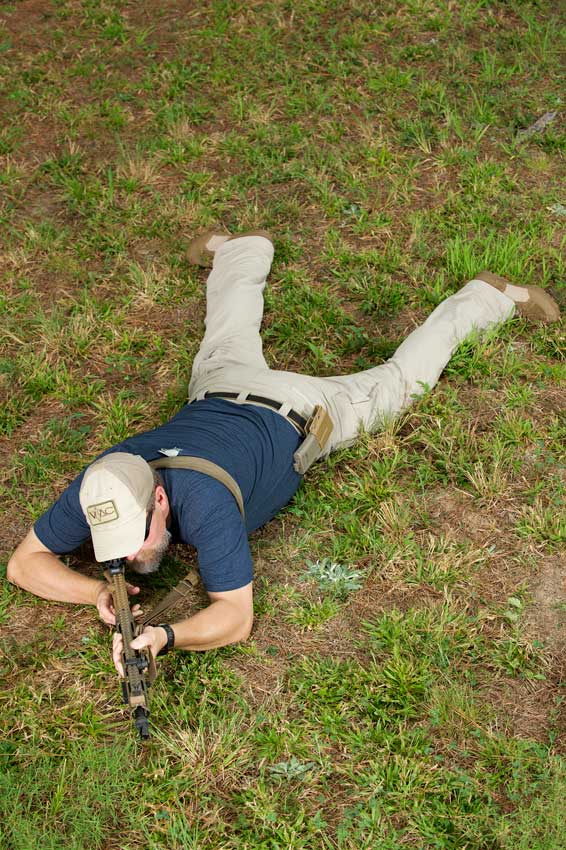 man outdoors grass laying down shooting rifle position training guns