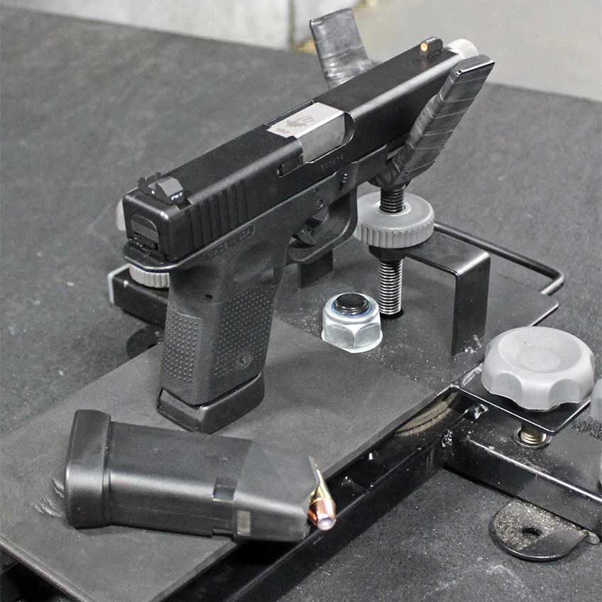 black handgun gun pistol in cradle shooting rest table ammo