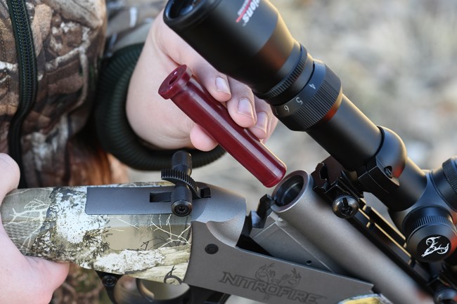 Federal Firestick being loaded into break-action muzzleloader outdoors camouflage clothing