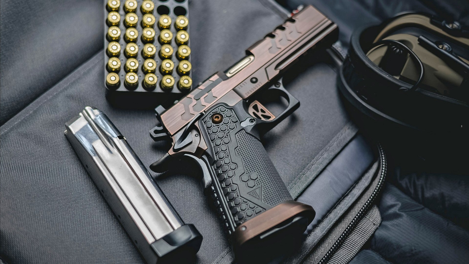 Kimber 2K11 Pro shown resting on a shooting bag, surrounded by a magazine, a box of ammunition and earmuffs.