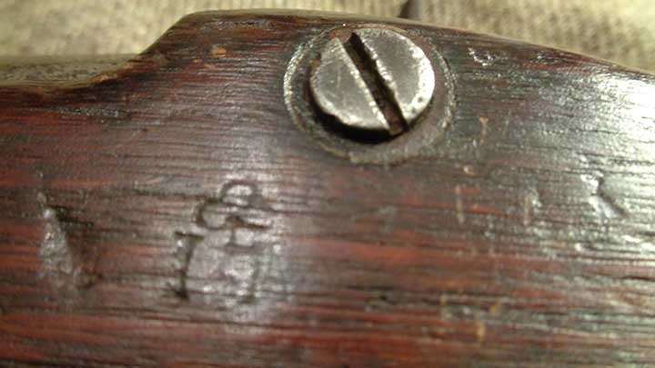 A shamrock and &quot;I N&quot; stamped into the stock of a Fenian Bridesburg rifle-musket between the lockplate screw heads.