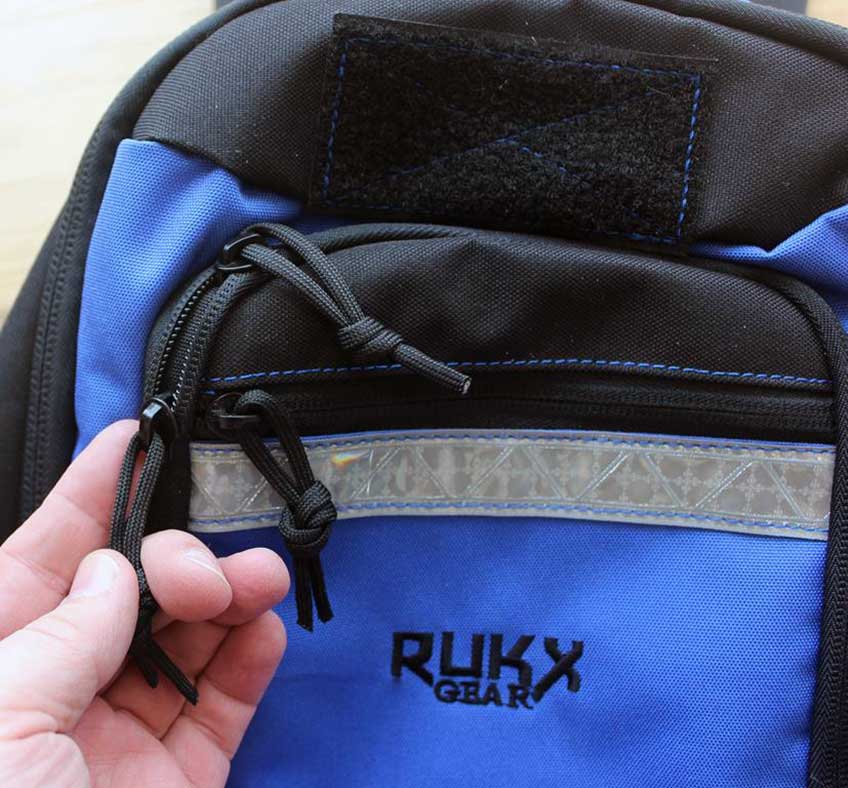 backpack Rukx gear fingers hand closeup zipper pulls tether