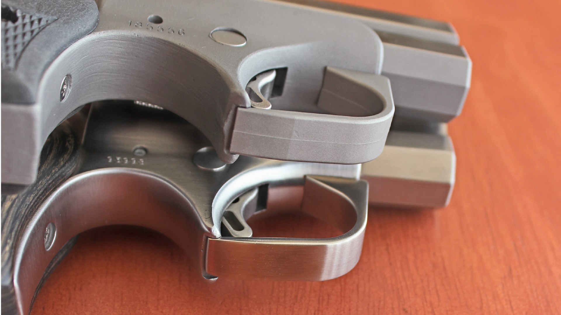 Bottom view of a Bond Arms Rough Series derringer sitting atop a Defender Series derringer.
